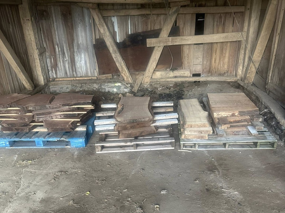 Live-edge hardwood slabs stacked on pallets in the Vail Wood Products barn, available in Butler, Indiana